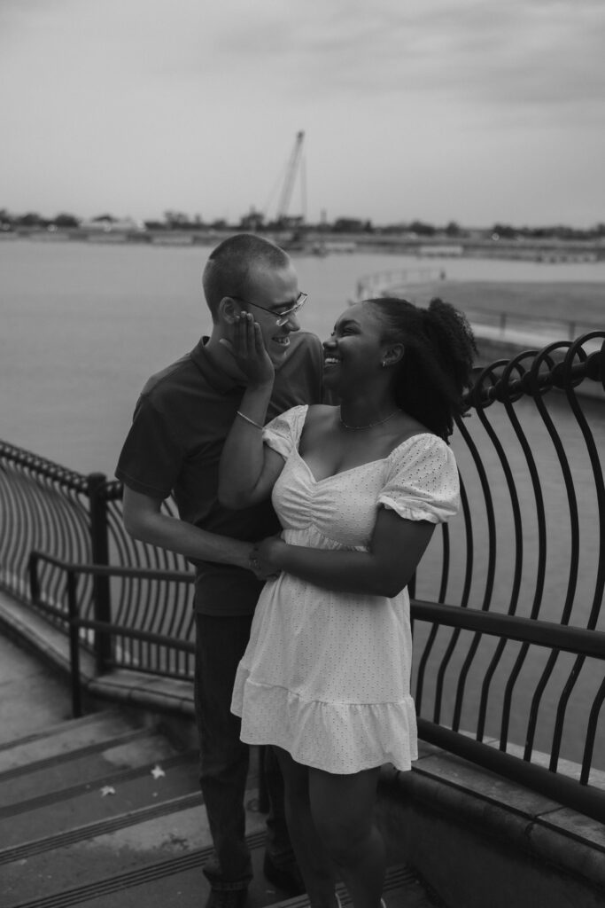 Black and white photo of an engaged couple in front of a lake in Rockwall, Texas