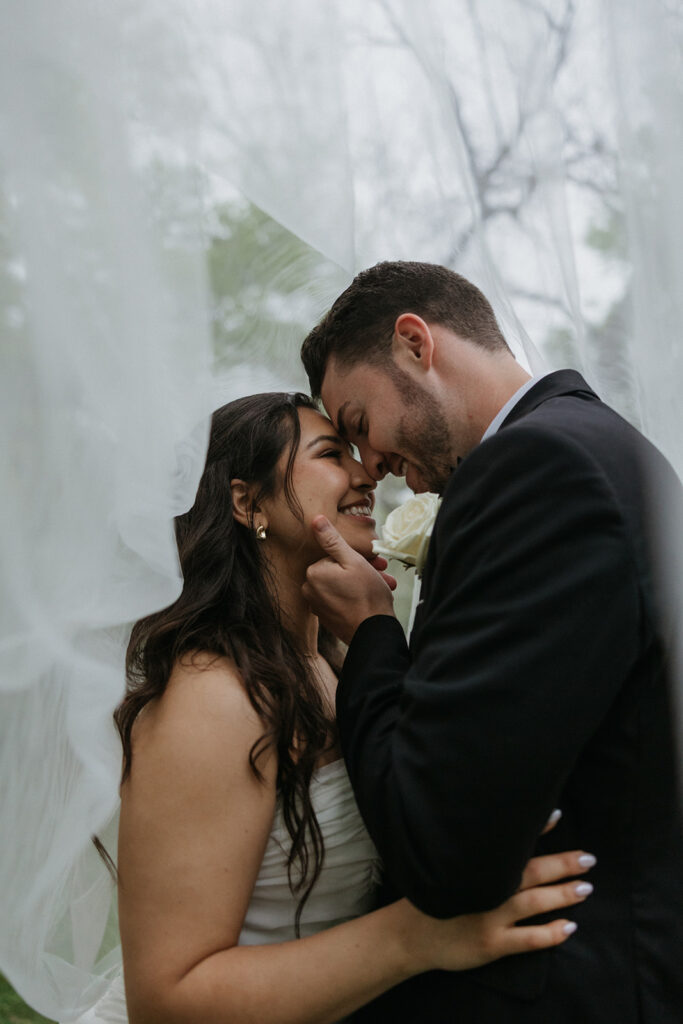 bride and groom smiling under the veil