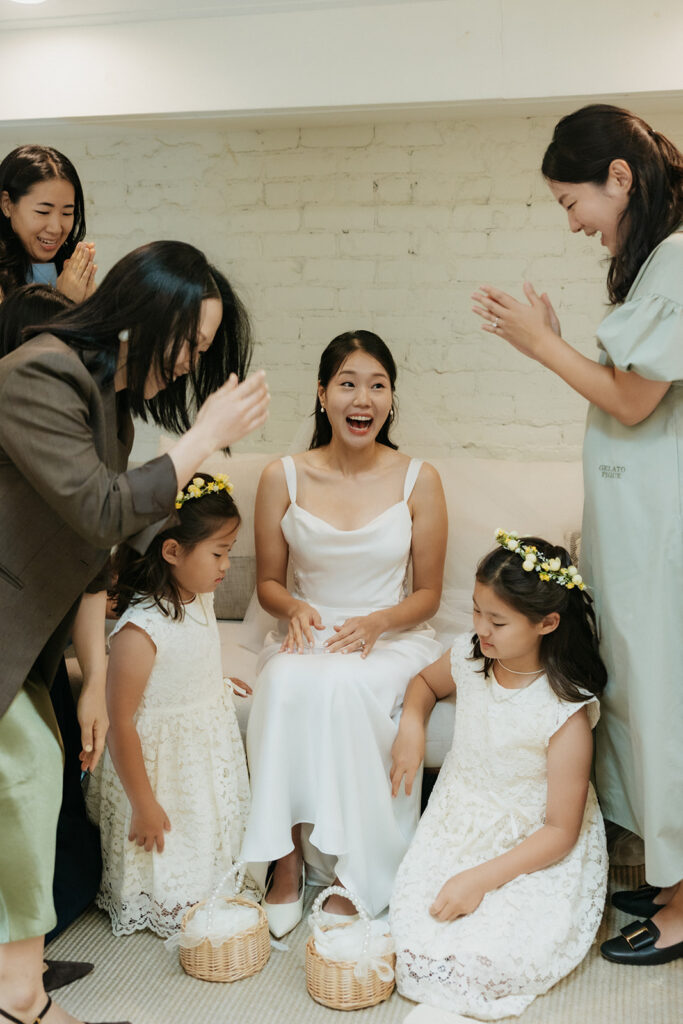 Bridal party clapping as the bride beams in excitement after the group prayer.