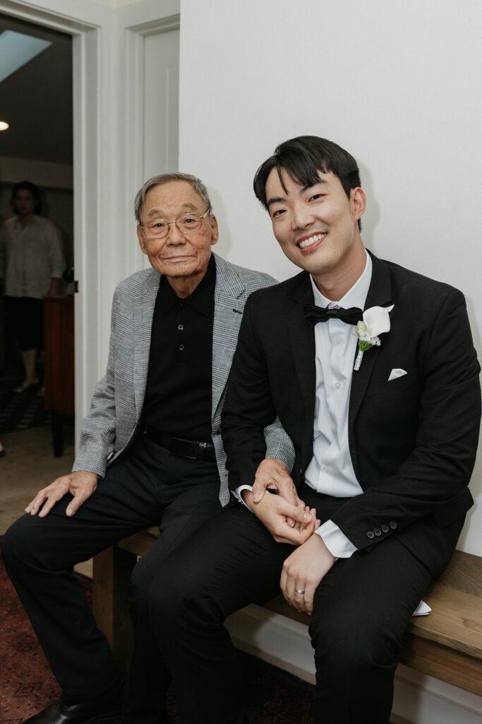 Groom and his grandfather sitting on a bench, enjoying time together.
