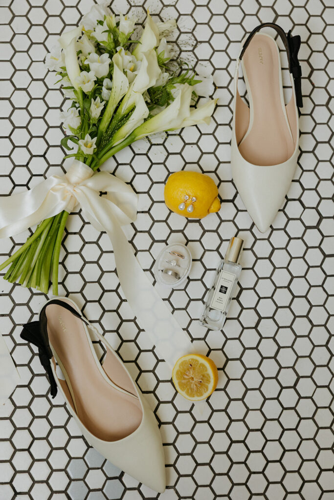 Bride accessories elegantly displayed on a black and white tile background with a bouquet and lemons.