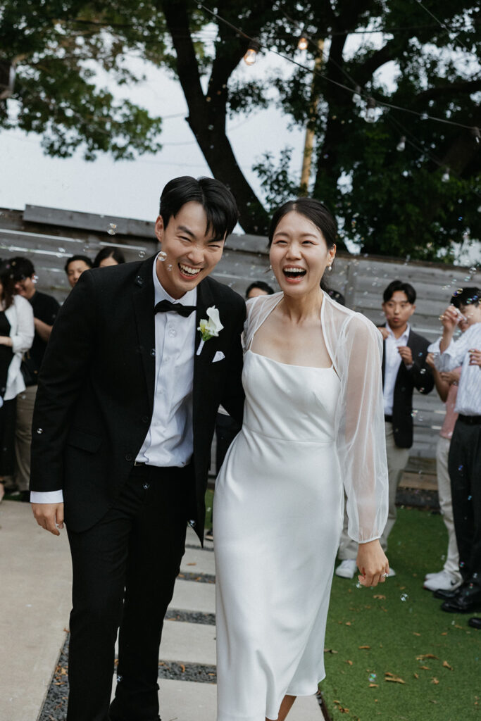 The newlywed couple walking while laughing during the bubble send-off.