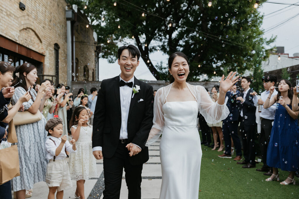 Bride and groom walk in excitement as the wedding guests send them off.