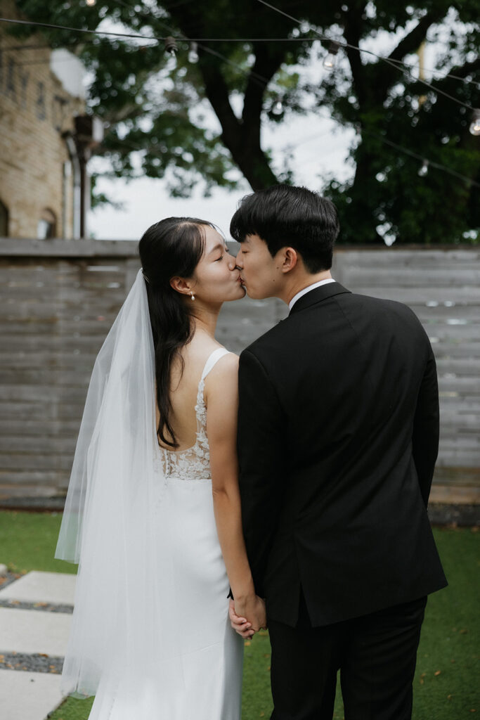 Bride and groom kissing and holding hands outside of One Eleven East Hutto Texas.