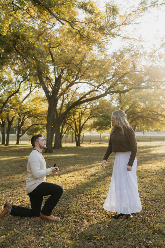 A man on one knee proposing to his girlfriend at Elmer W. Oliver Nature Park.