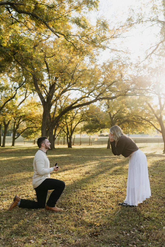 A man proposing and a girl in disbelief during a surprise proposal at Elmer W. Oliver Nature Park. 