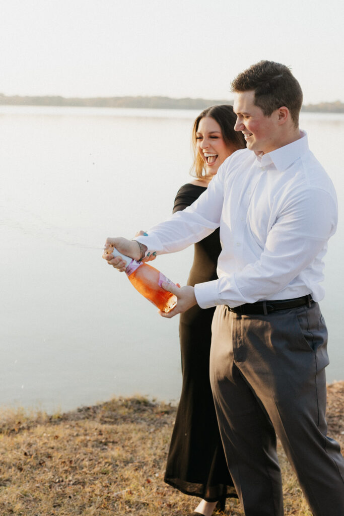 Couple popping champagne to celebrate their proposal at Lake Waco.