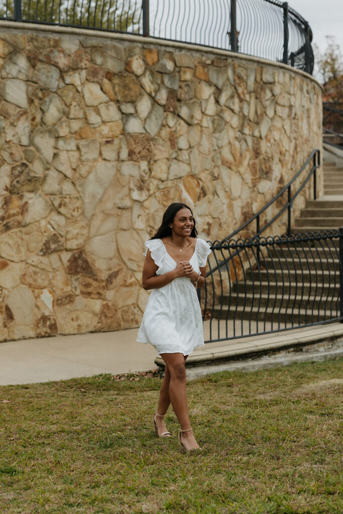 A woman smiling as she sees the romantic proposal set up for her.