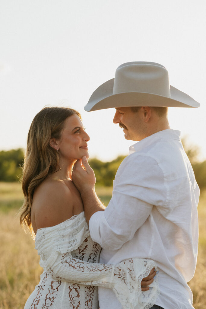 Newly engaged couple looking into each others eyes during summer engagement photos at golden hour.