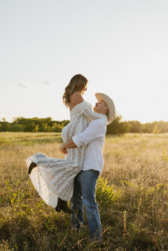 Man holding his fiancée in the air during summer engagement photos.