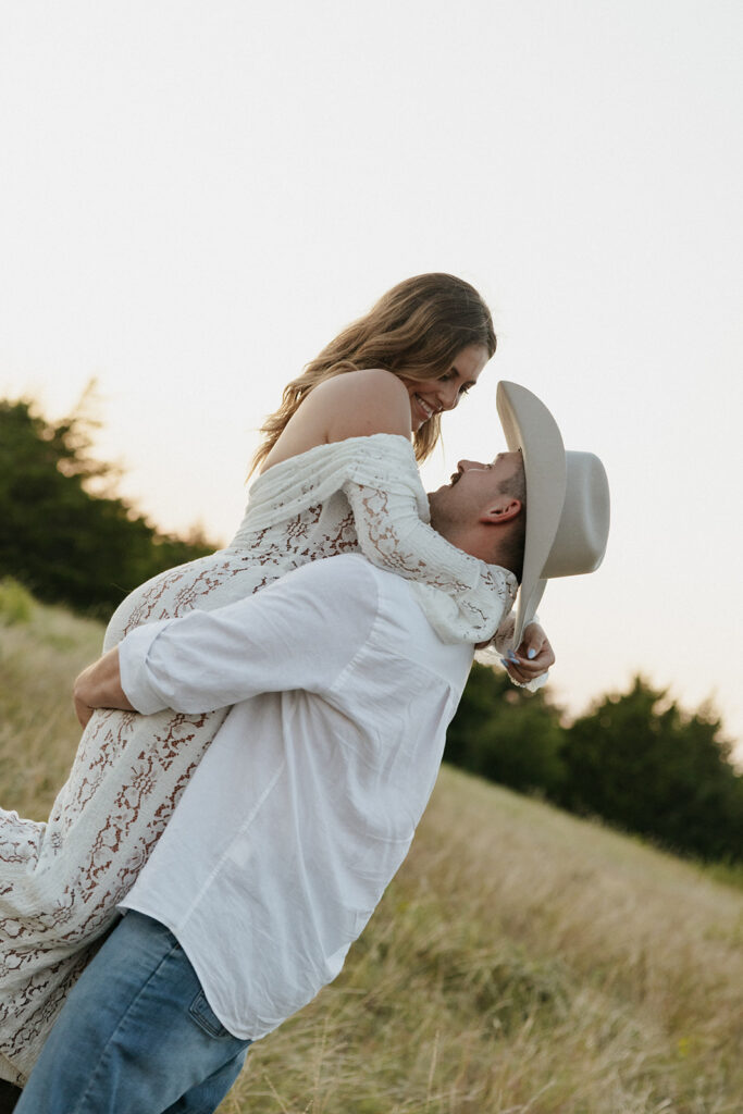 Couple romantically looking at each other as they spin in an open field for summer engagement photos.