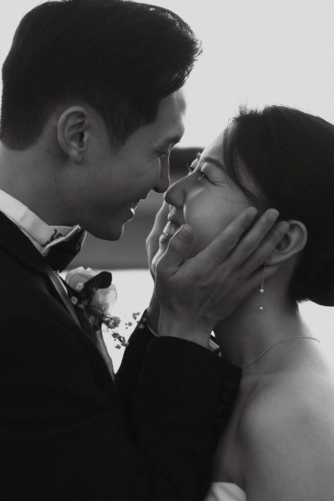 Groom holding the bride's cheeks as he looks into her eyes romantically. 