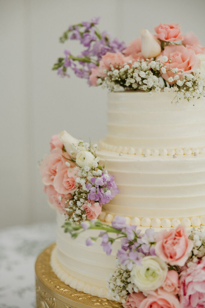 Elegant wedding cake with colorful florals and a gold base.