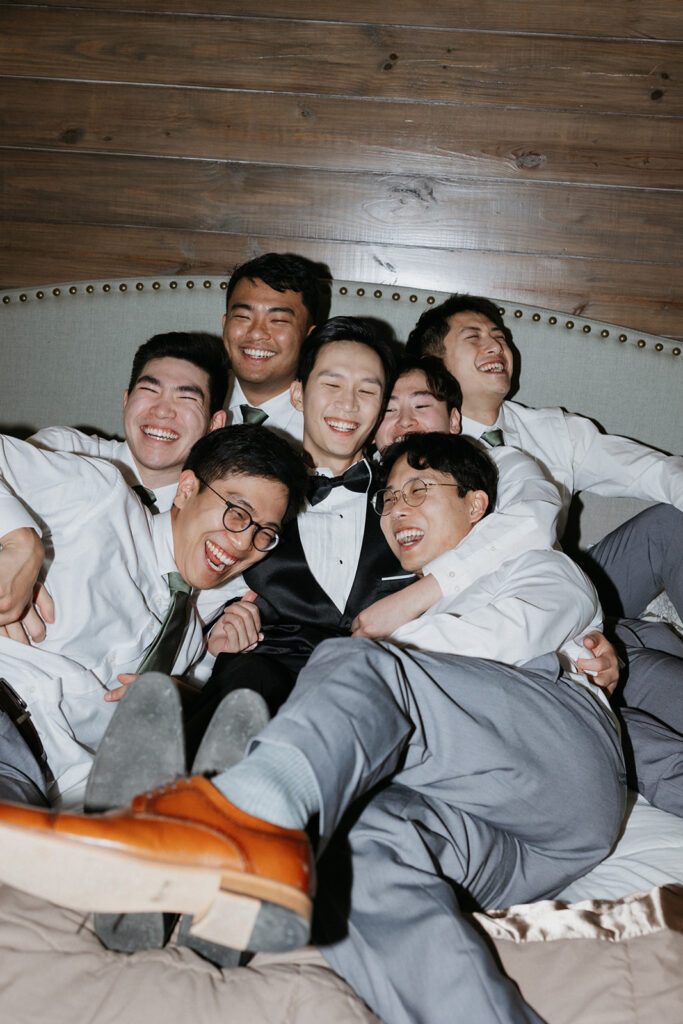 Groomsmen making a funny pose on a bed at Bella Cavalli Events.