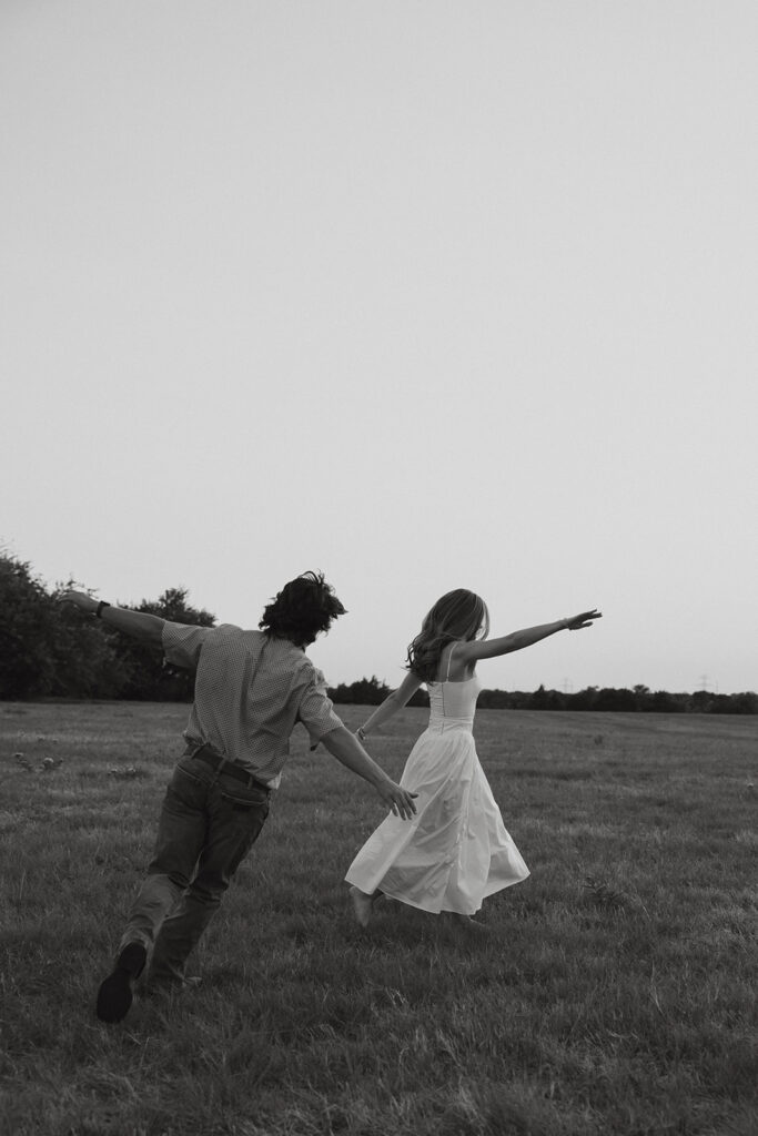 A couple playfully running around with their hands in the air.