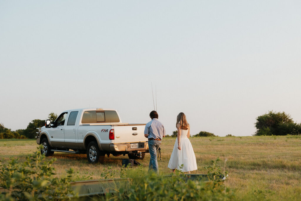A couple walking back to their truck with fishing poles in their hands.