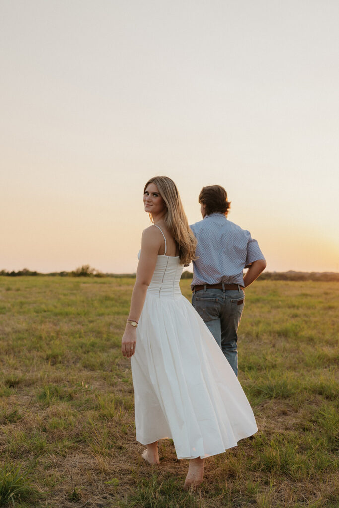 Dallas engagement photography of a woman walking behind her fiancé.