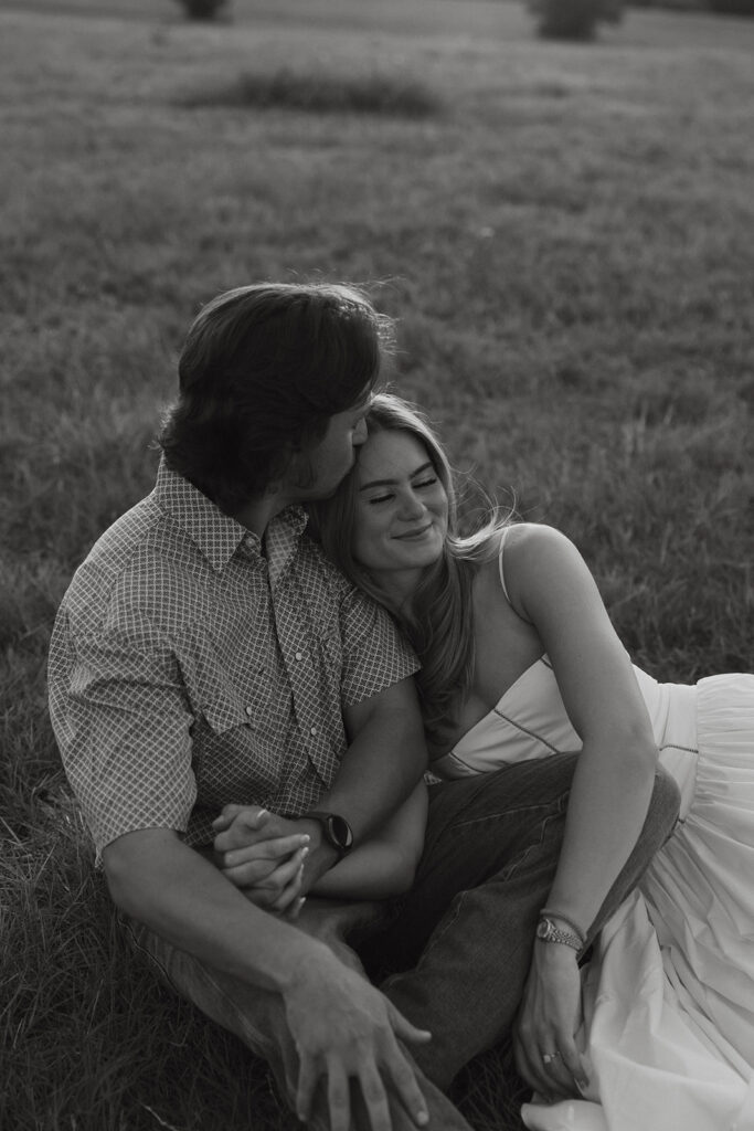 A couple sitting in the grass in a field in Rockwall, Texas.