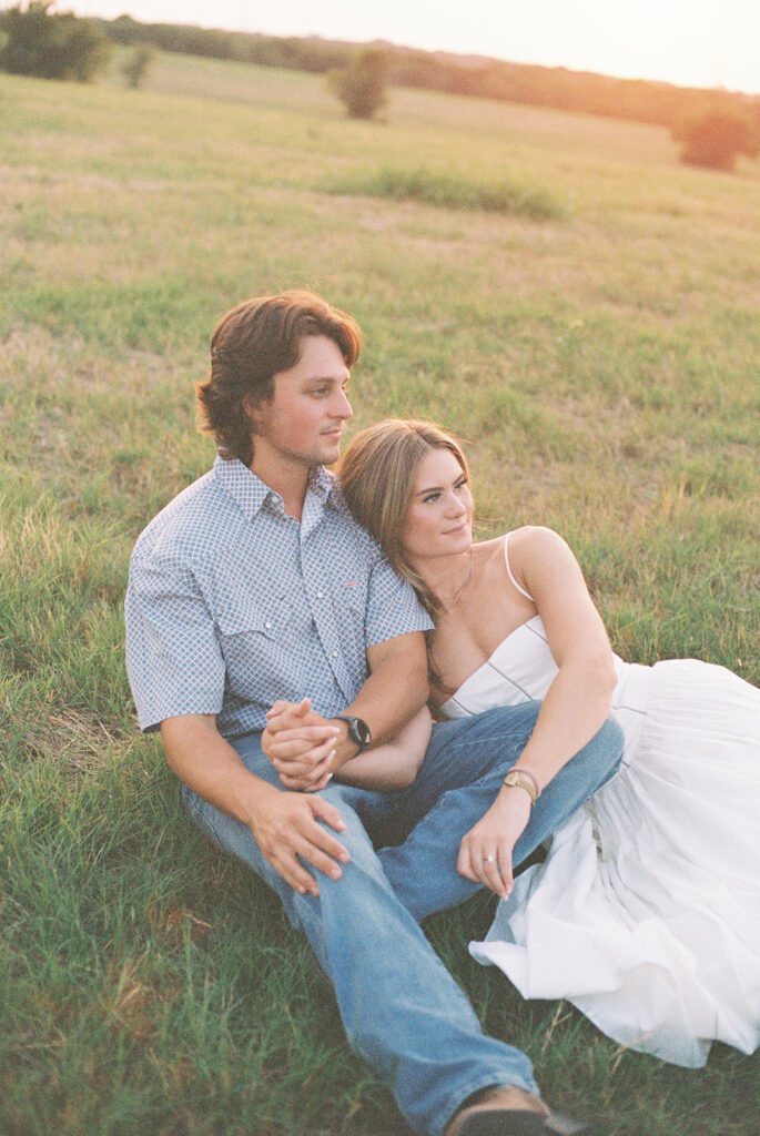 Film engagement photos of a couple laying in the grass in a field in Dallas.