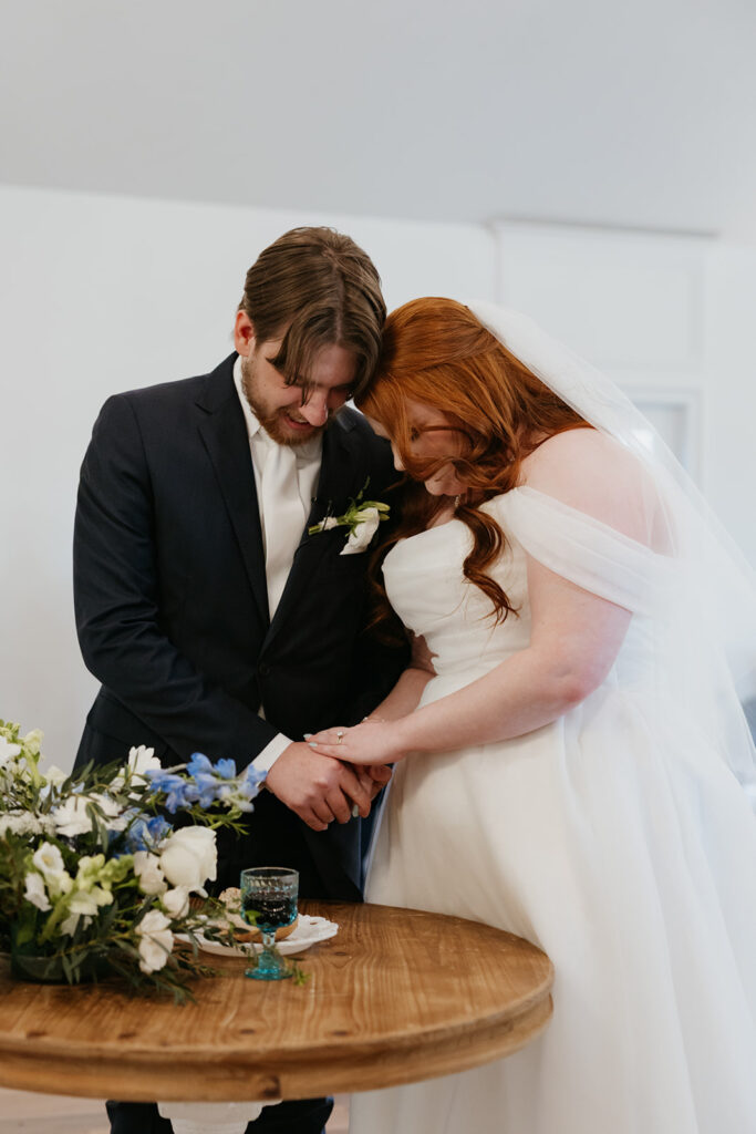 Bride and groom holding hands and praying before communion.
