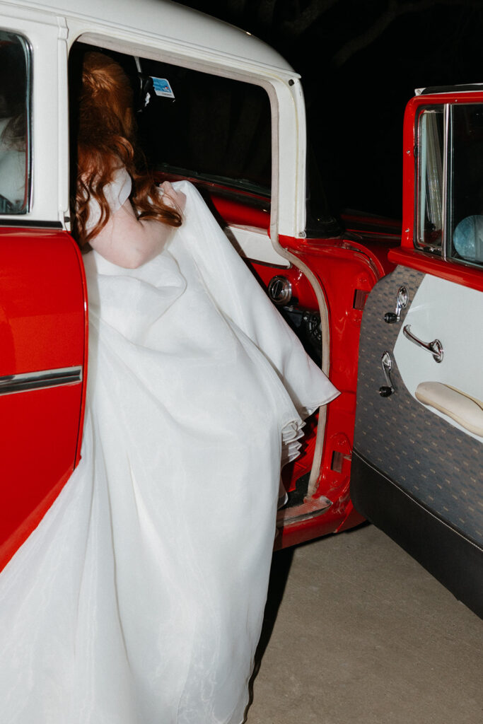 Bride getting into a vintage car.