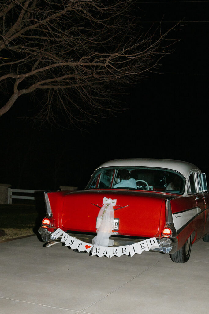 Newlyweds driving away from The Nest at Ruth Farms in a vintage car.