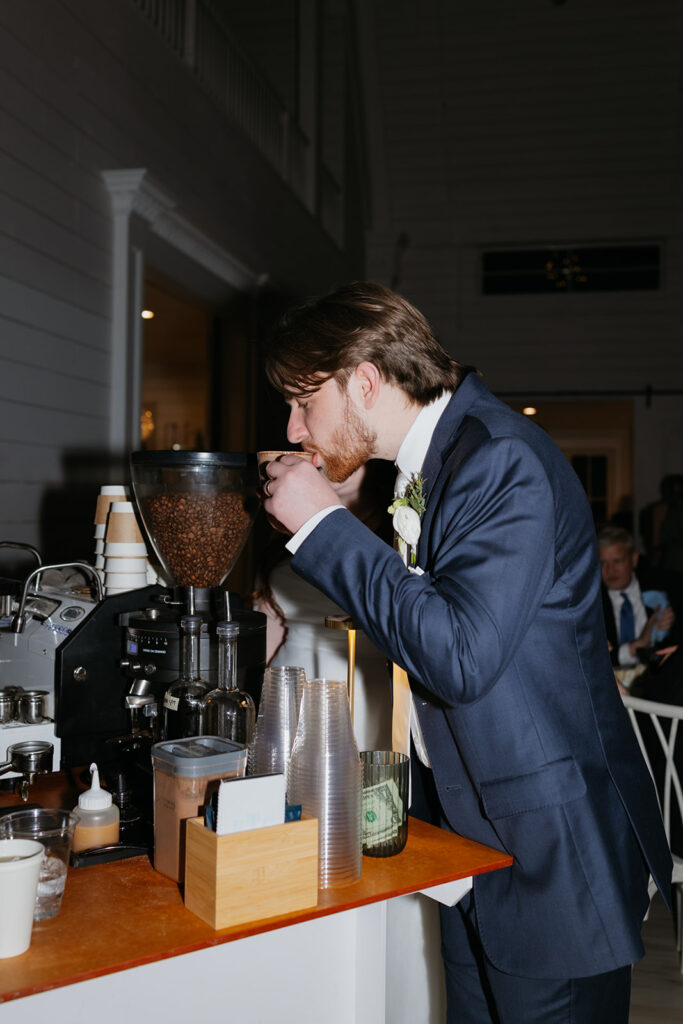 Groom drinking coffee at a coffee bar at the wedding reception.