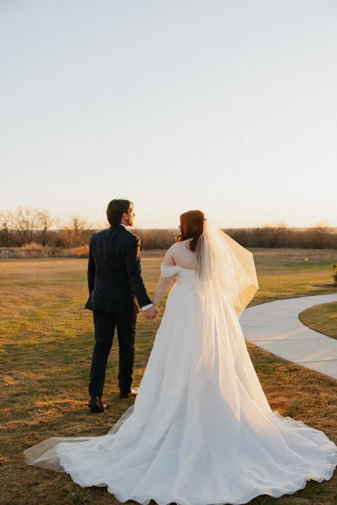 Bride and groom holding hands while looking off into the distance at The Nest at Ruth Farms.