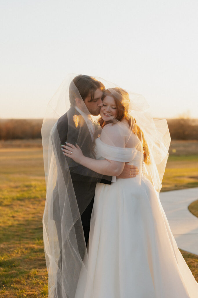 Groom kissing his bride's cheek during golden hour at The Nest at Ruth Farms.