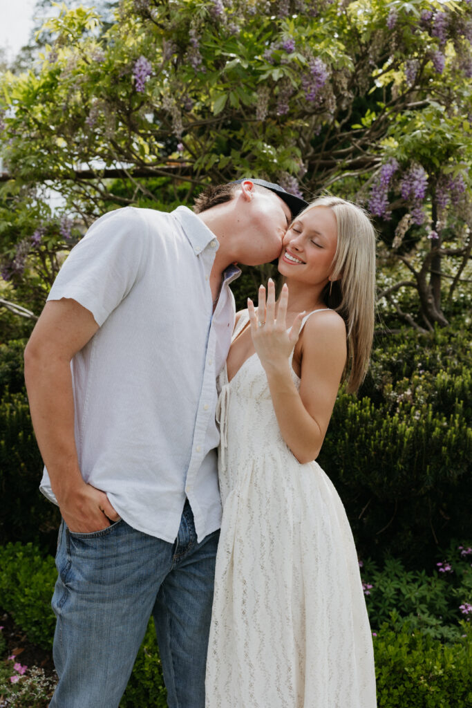 A man kissing the cheek of his fiancée during their Dallas Arboretum and Botanical Garden proposal.