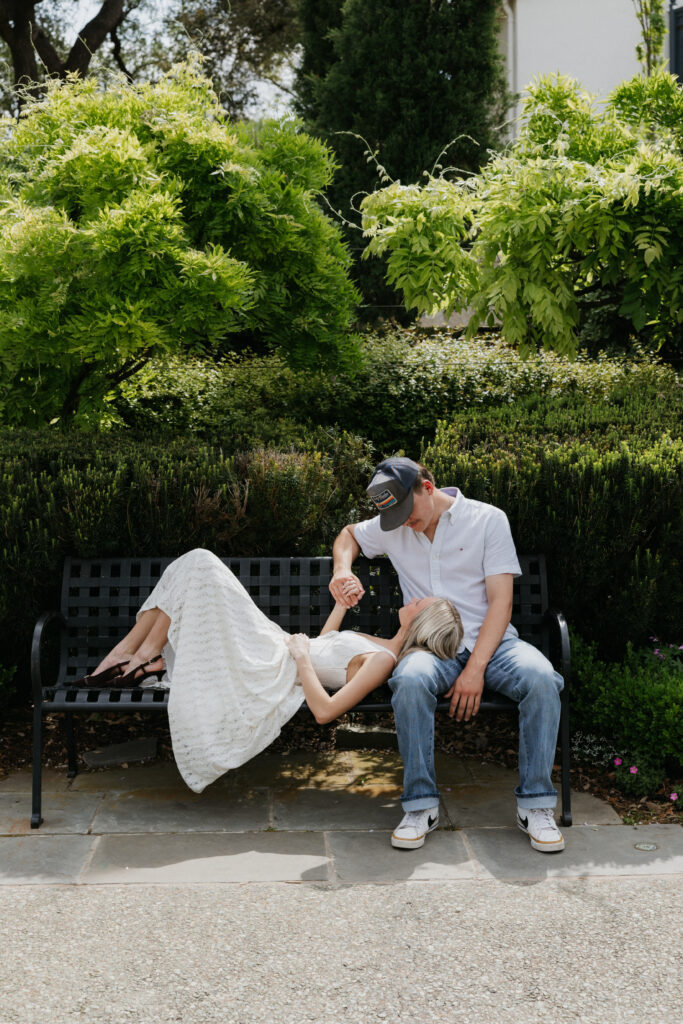 A couple lying on a bench during their Dallas Arboretum and Botanical Garden proposal.