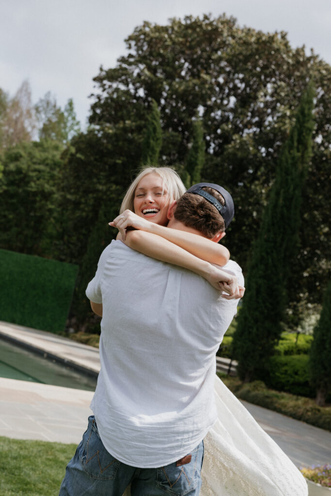 A woman smiling as her fiancé spins her around. 