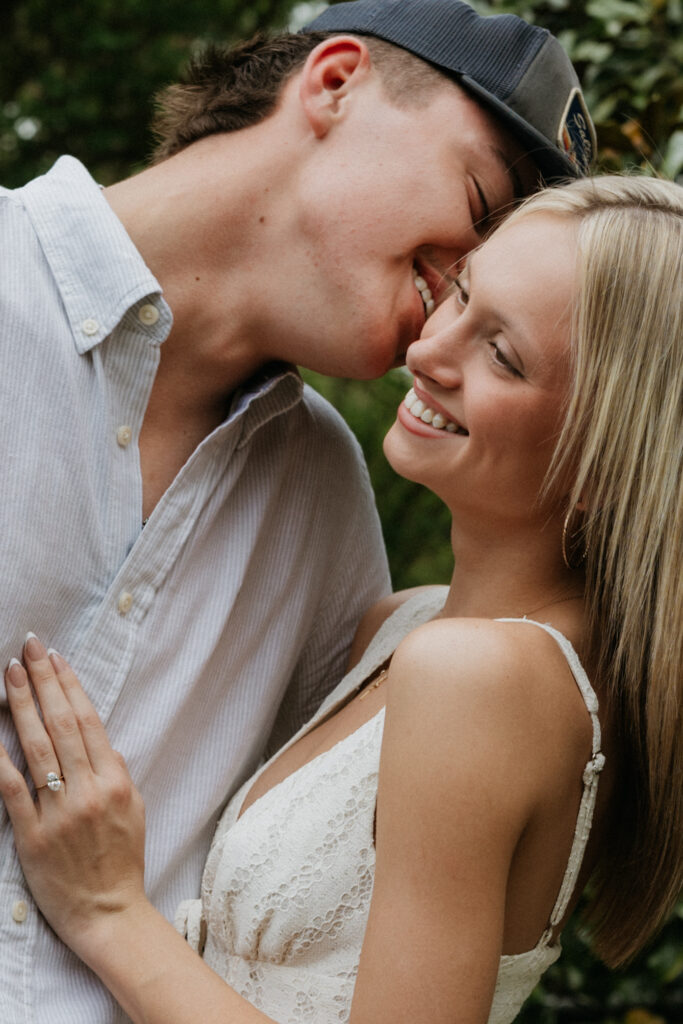 A man going in to kiss his fiancée during their Dallas Arboretum and Botanical Garden proposal.