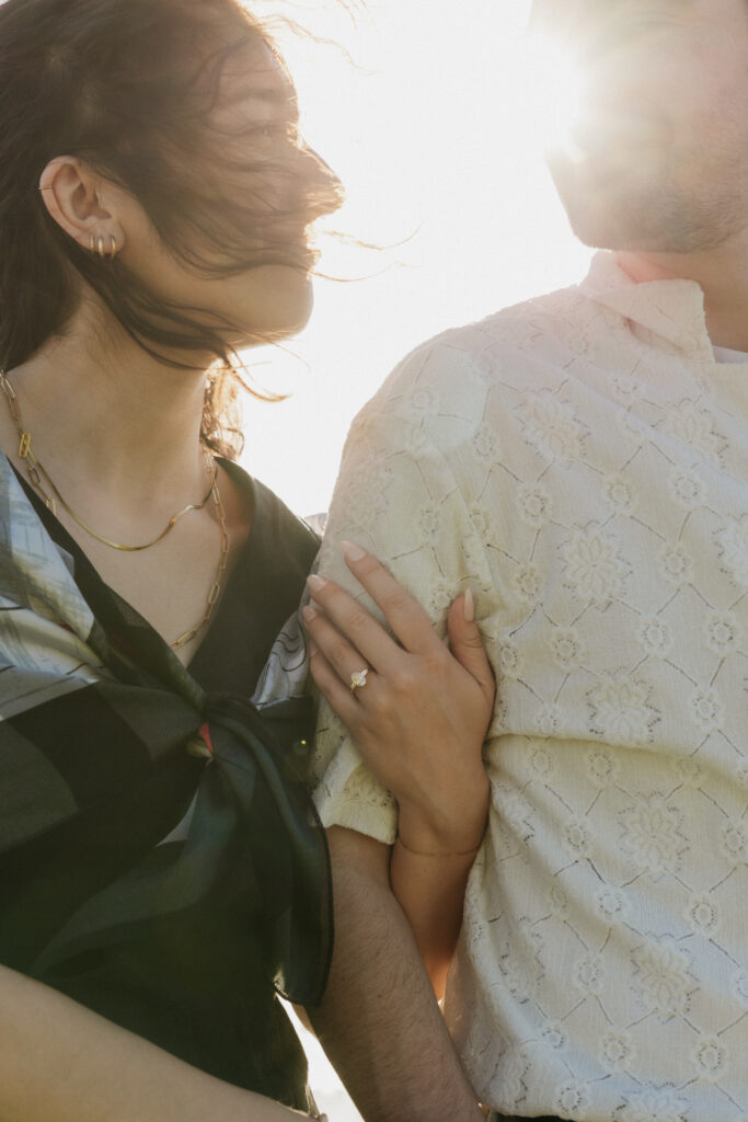 A woman with her arm wrapped around her fiancé arm during their proposal.