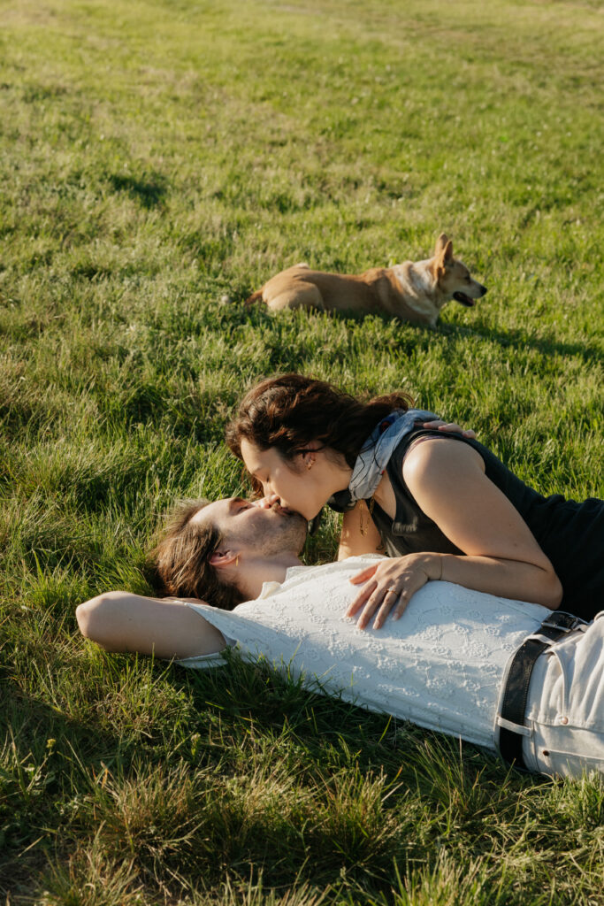 A couple lying in the grass, kissing. 