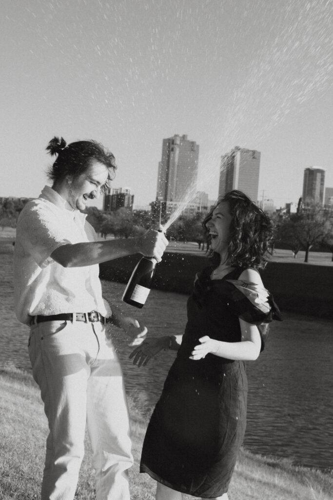 A couple spraying champagne at Trinity River, one of the best places to propose in Fort Worth.