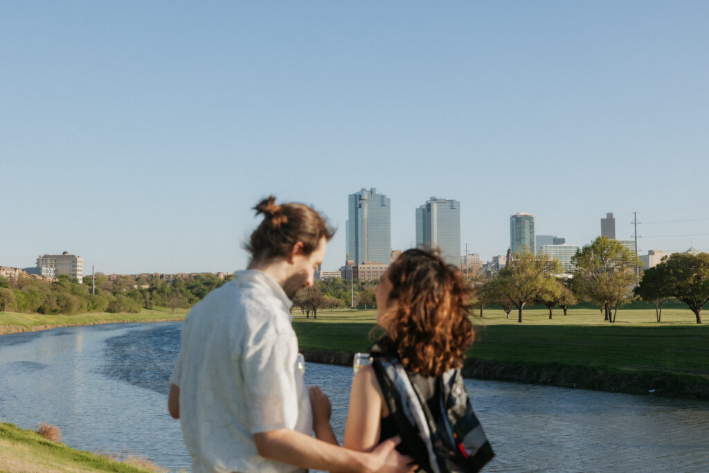 A couple laughing together by a river in downtown Fort Worth.