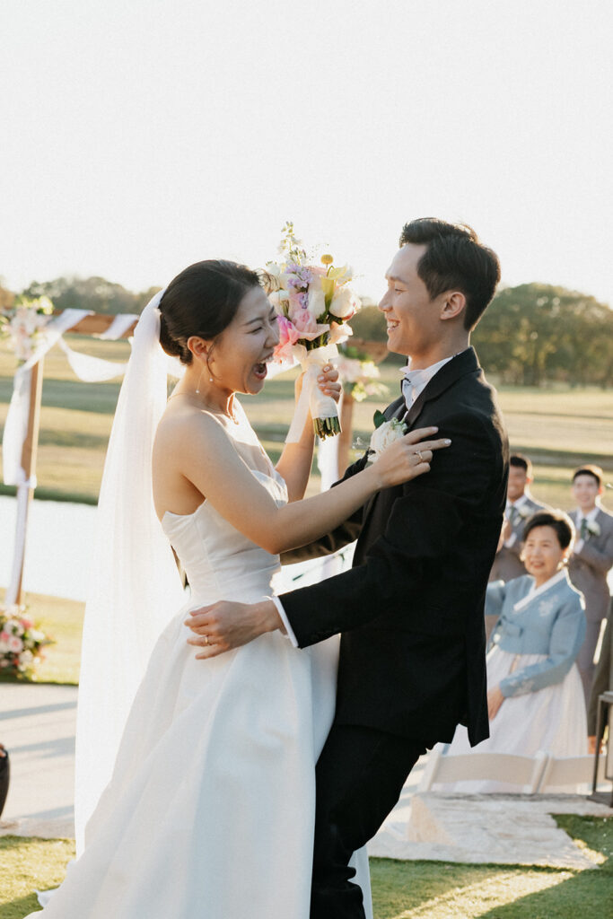 Bride and groom holding one another while celebrating at their summer wedding. 