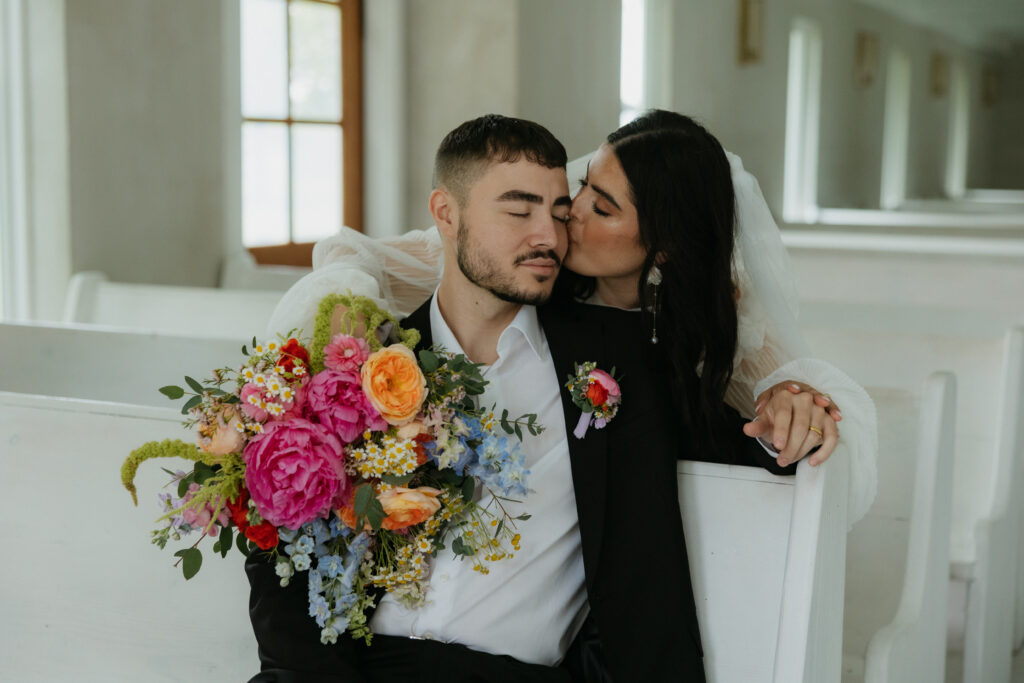 Bride kissing her husbands cheek. 