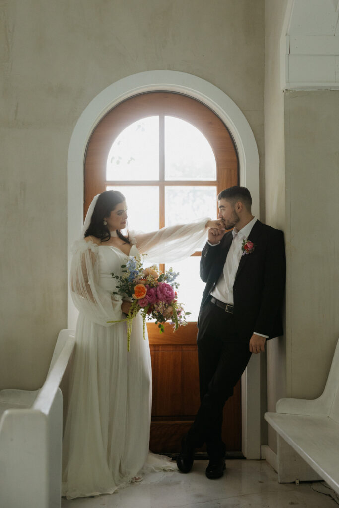 A groom kissing his bride's hand. 