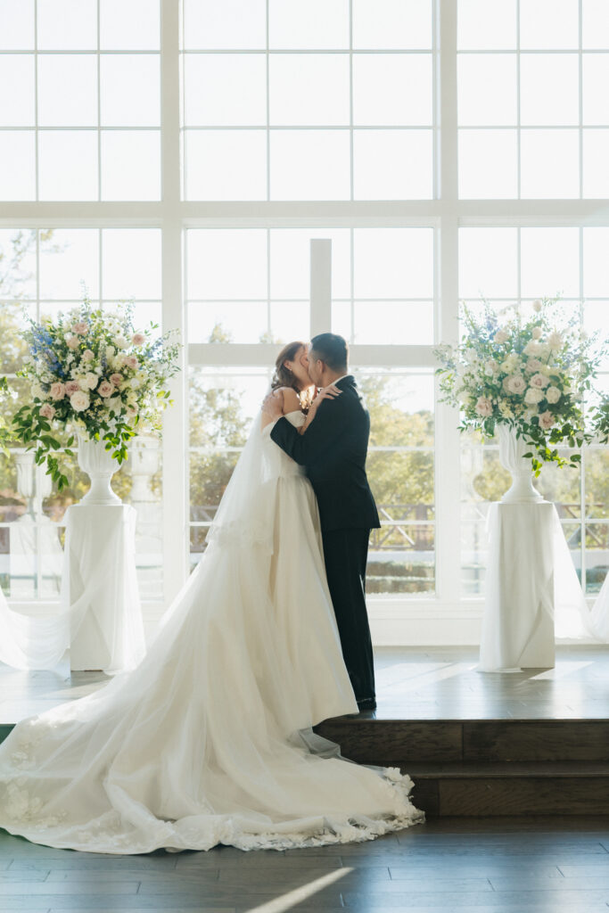 Bride and groom kissing at the altar of their DFW wedding venue.