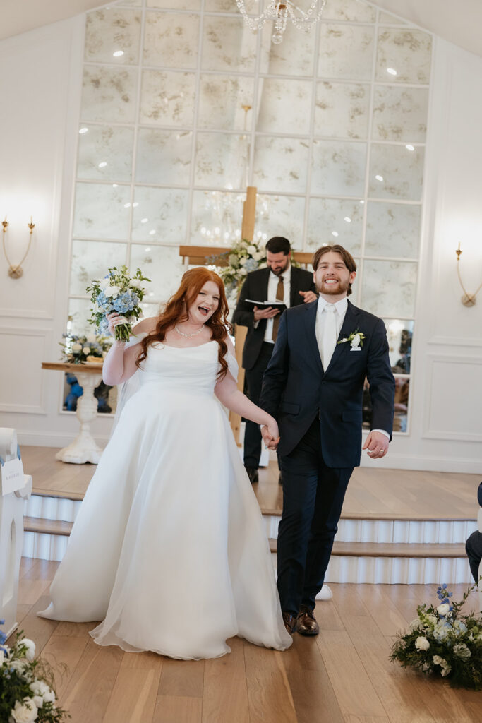 Bride and groom walking happily down the aisle of their summer wedding. 