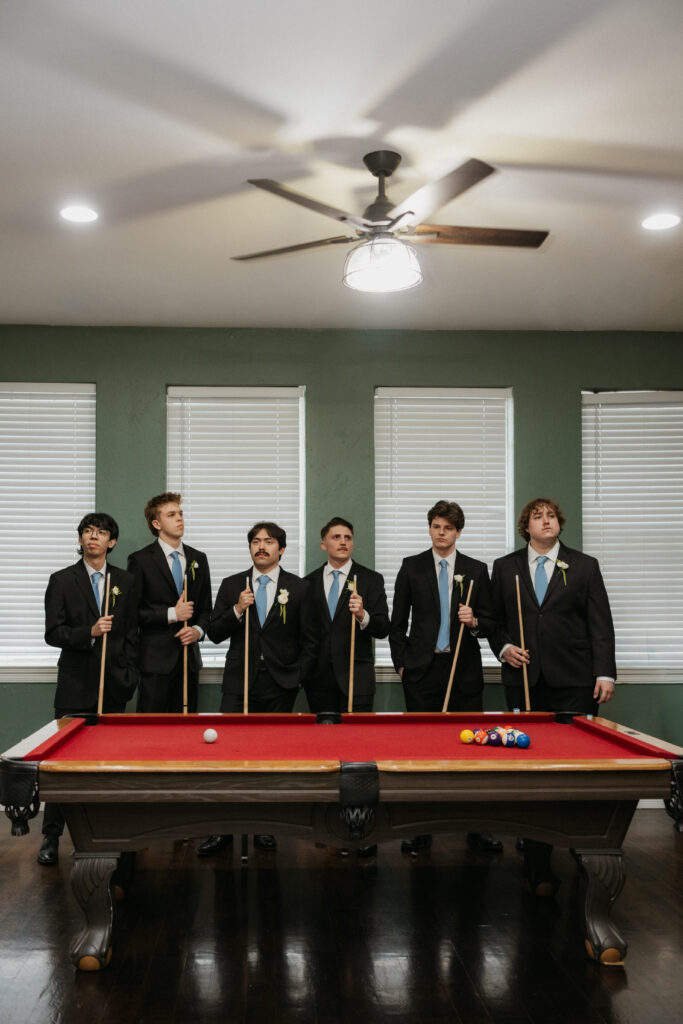 Groomsmen standing at a pool table at The Springs Valley View in Texas.