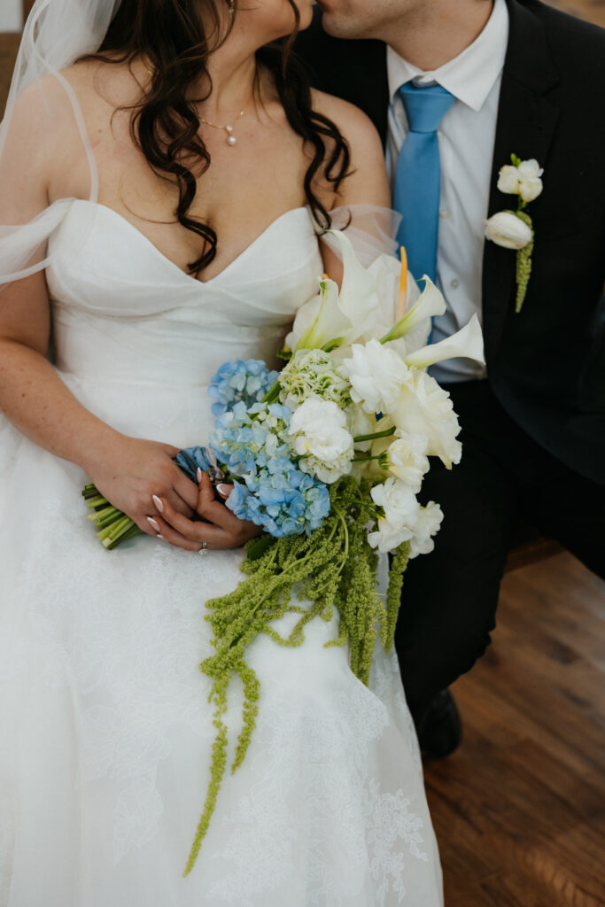 Bride and groom sitting together, kissing.