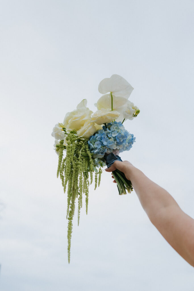 Bride holding her wedding flowers in the air.
