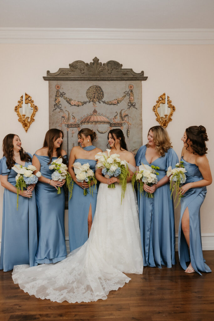 Bridal party in blue dresses standing with the bride.