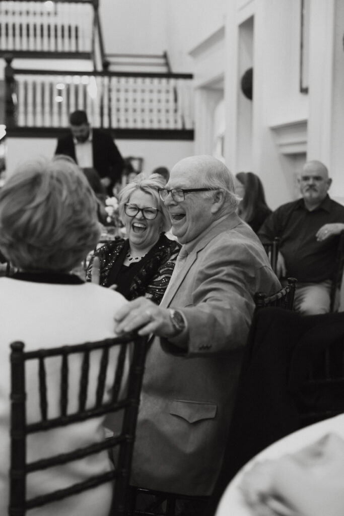 Wedding guests laughing together while seated at a table. 