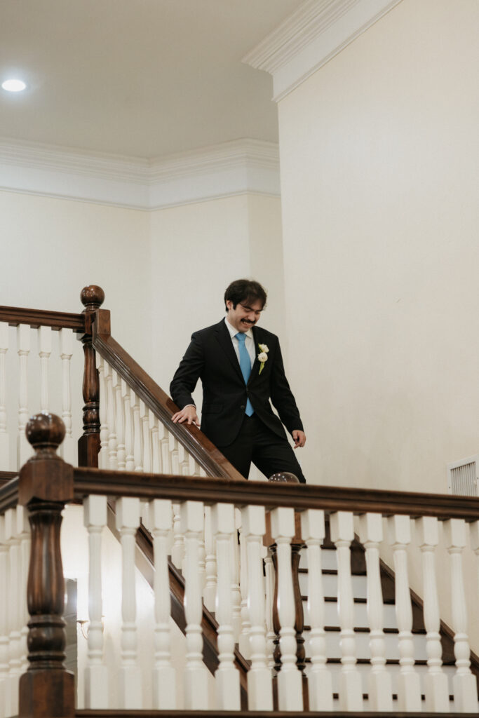 Groom running down the staircase fo the reception.