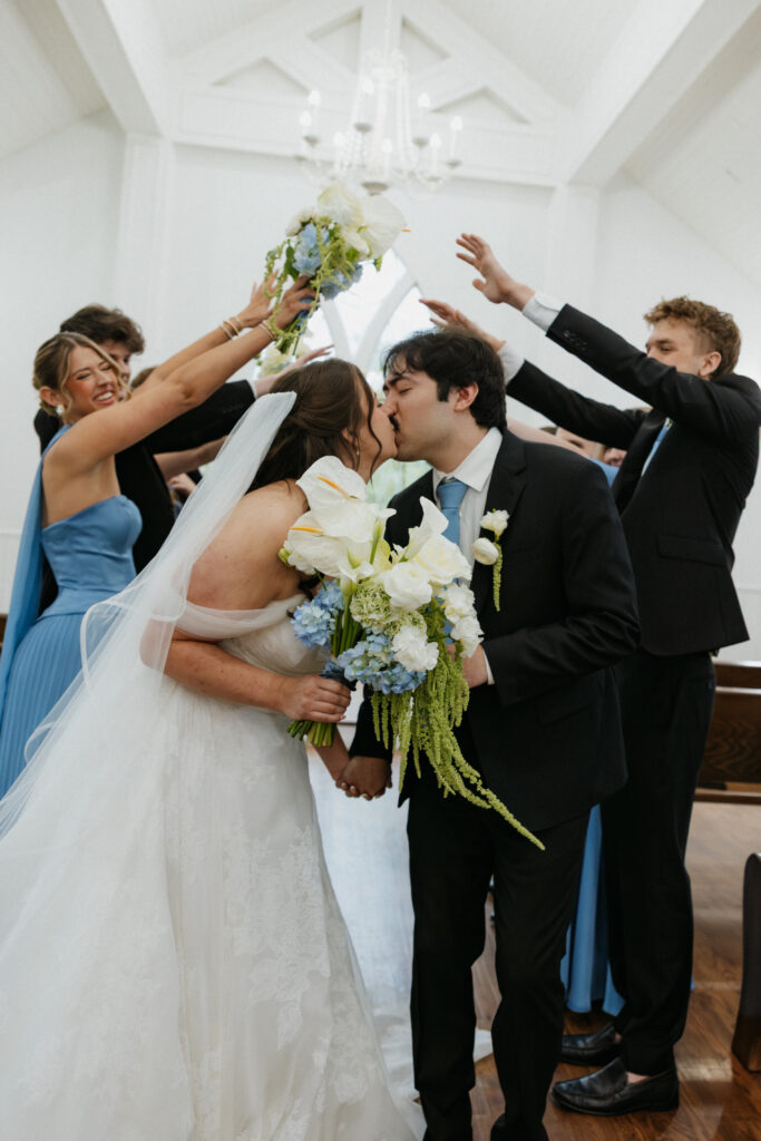 Wedding party cheering as the couple kisses. 