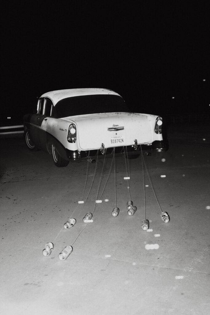 A vintage car driving away from the wedding reception. 